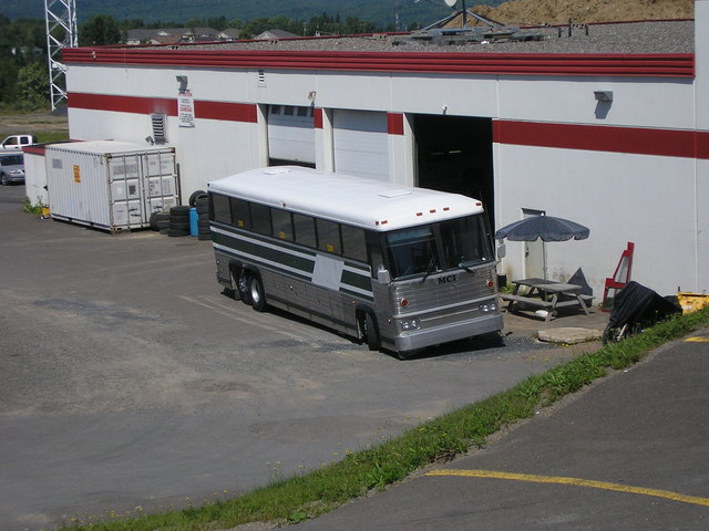 Green/White MCI Bus in front of shop, Fredericton, N.B.